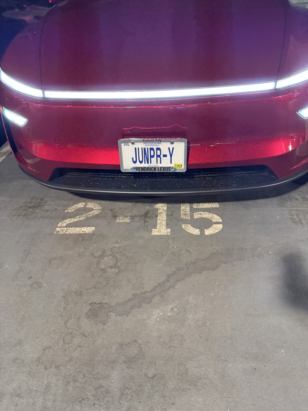Front of the red Tesla Model Y in a parking garage wearing its original Missouri plate, JUNPR-Y.