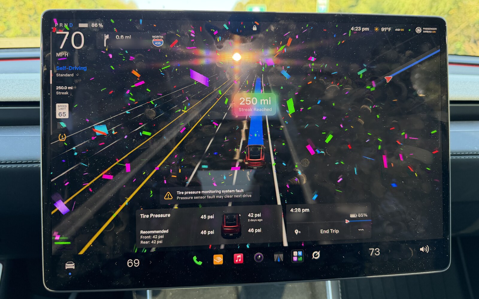 Tesla Model Y center screen on I-435 North at 70 mph with Self-Driving on Standard, confetti across the display and a 250 mi Streak Reached badge. Below it, a yellow tire pressure monitoring system fault, and a tire card where the front passenger tire still shows 42 psi from 2 days ago.