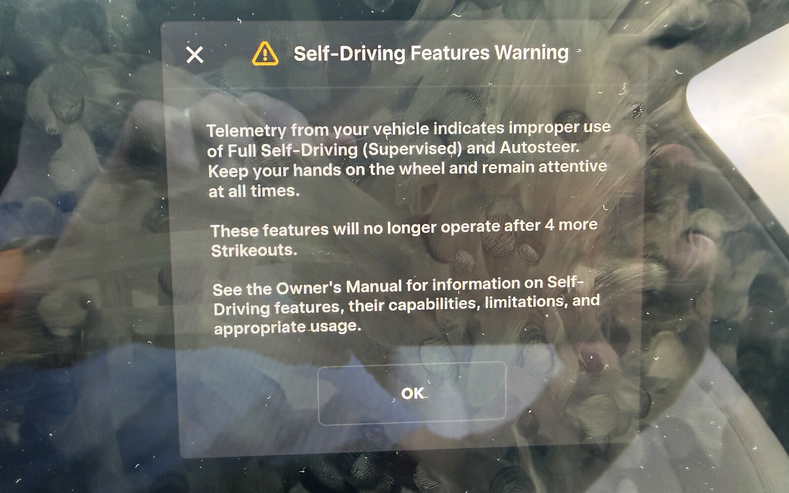 Tesla touchscreen showing a Self-Driving Features Warning about improper use of Full Self-Driving, warning that the features stop working after four more strikeouts.